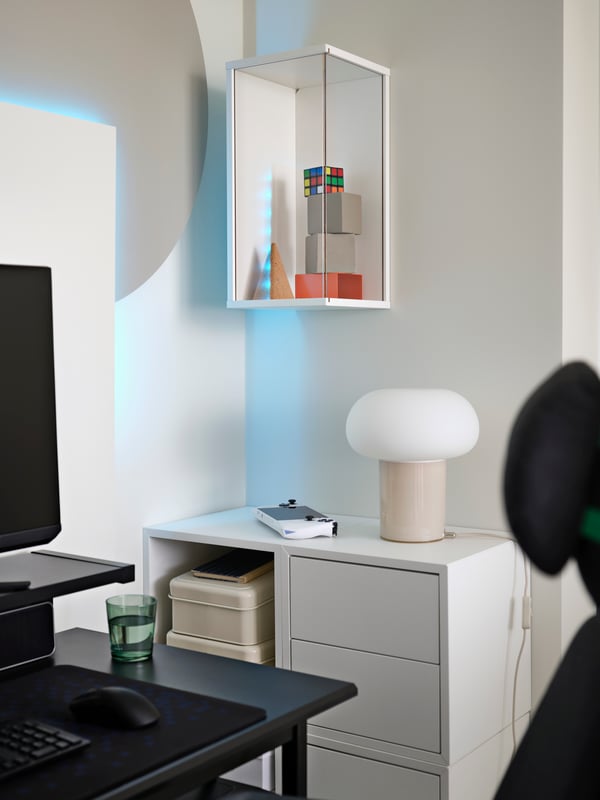 A white BRÄNNBOLL wall-mounted display cabinet with transparent plastic panels is vertical on wall and holds various cubes.