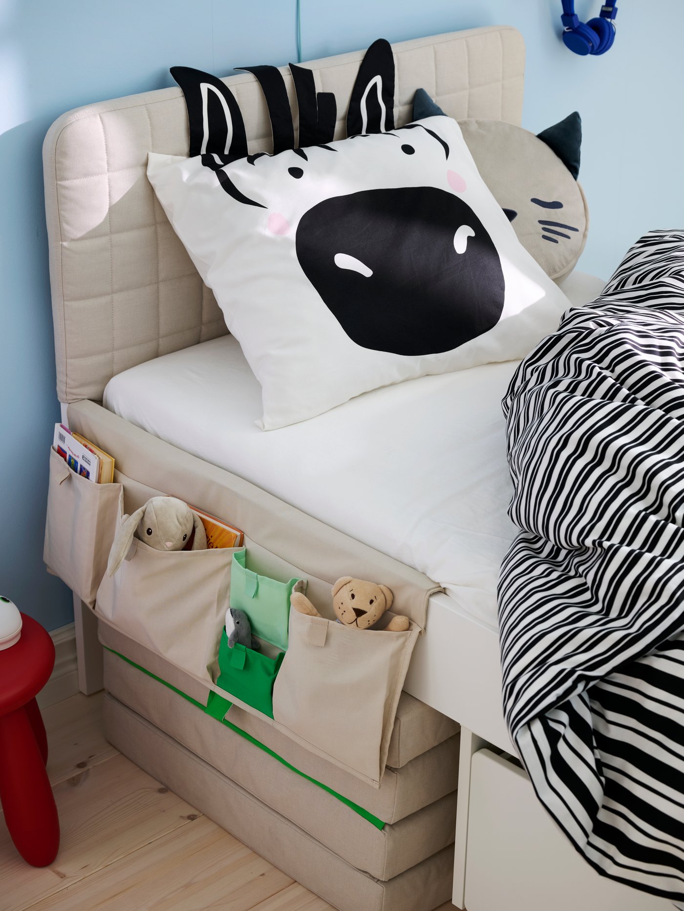 Gros plan sur un lit SLÄKT avec poche rangement pour lit MÖJLIGHET et housse de couette et taies d’oreiller NATTHÄGER avec imprimé zèbre.