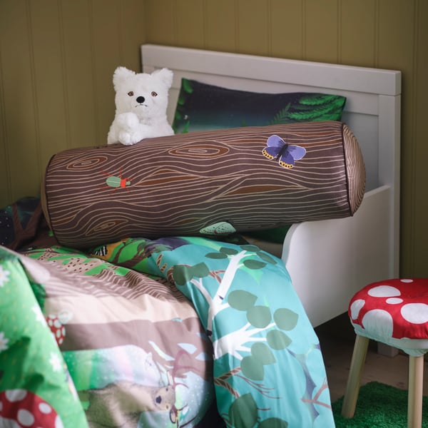 A cylinder shaped/brown SKOGSDUVA cushion in the childrens room