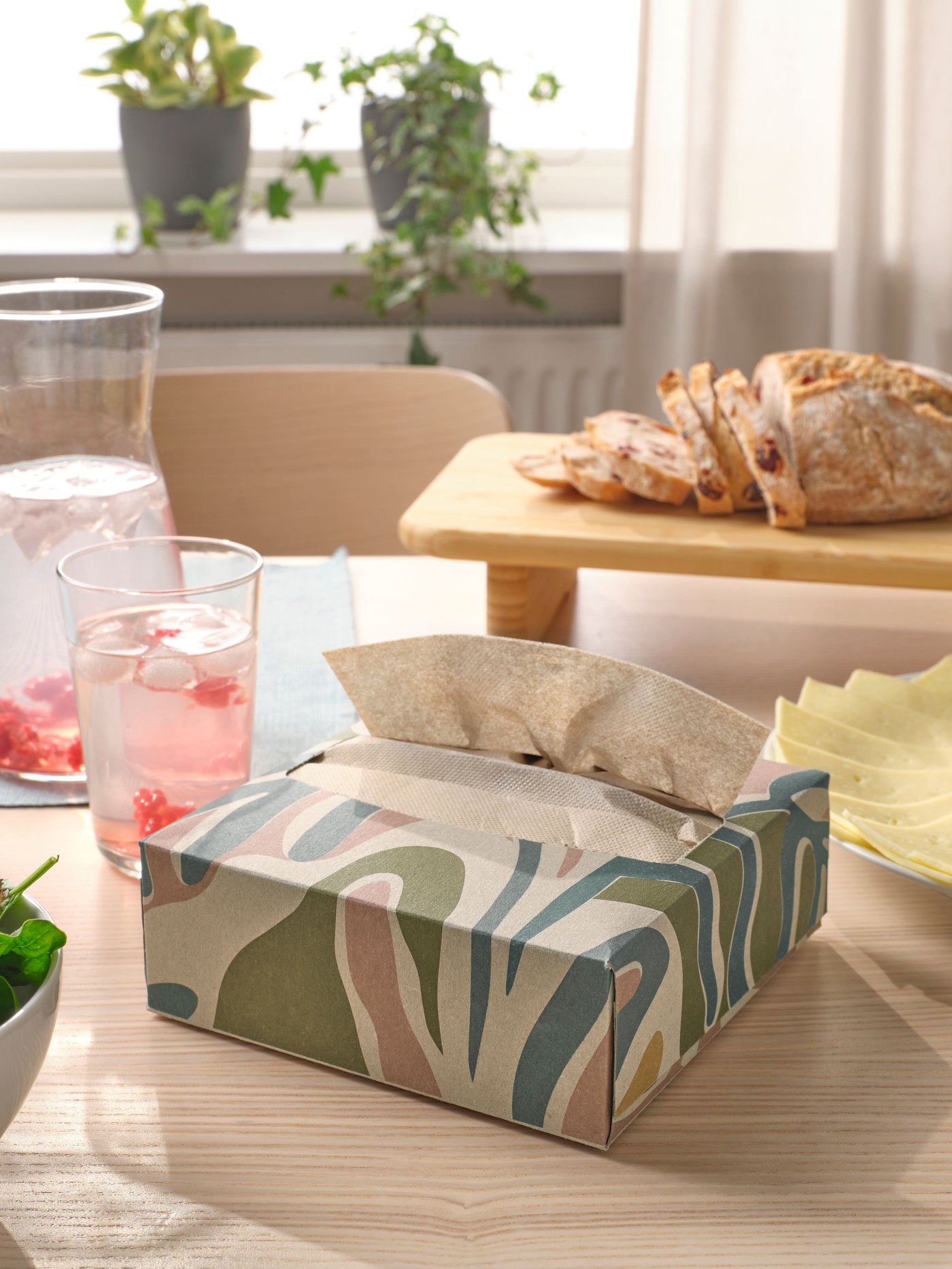 A patterned SLÖJSTJÄRT paper napkins on top of light wooden dining table.