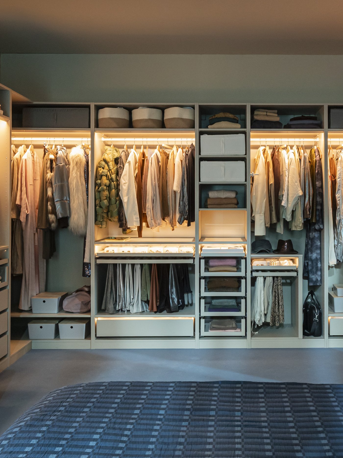 Camera da letto moderna con armadio IKEA a vista ben organizzato, illuminazione integrata e letto in primo piano. L’ambiente è ordinato e accogliente, con spazi dedicati a vestiti, accessori e oggetti personali.