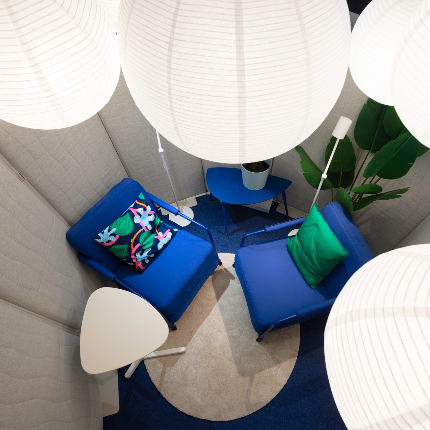 Un coin salon intimiste avec des fauteuils IKEA bleus, un éclairage doux et des coussins colorés crée un endroit paisible où se retirer.
