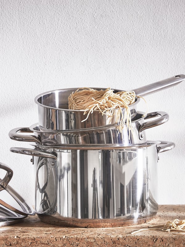 Pots of different sizes from the IKEA 365+ series are stacked inside each other with noodles hanging out from the top one.