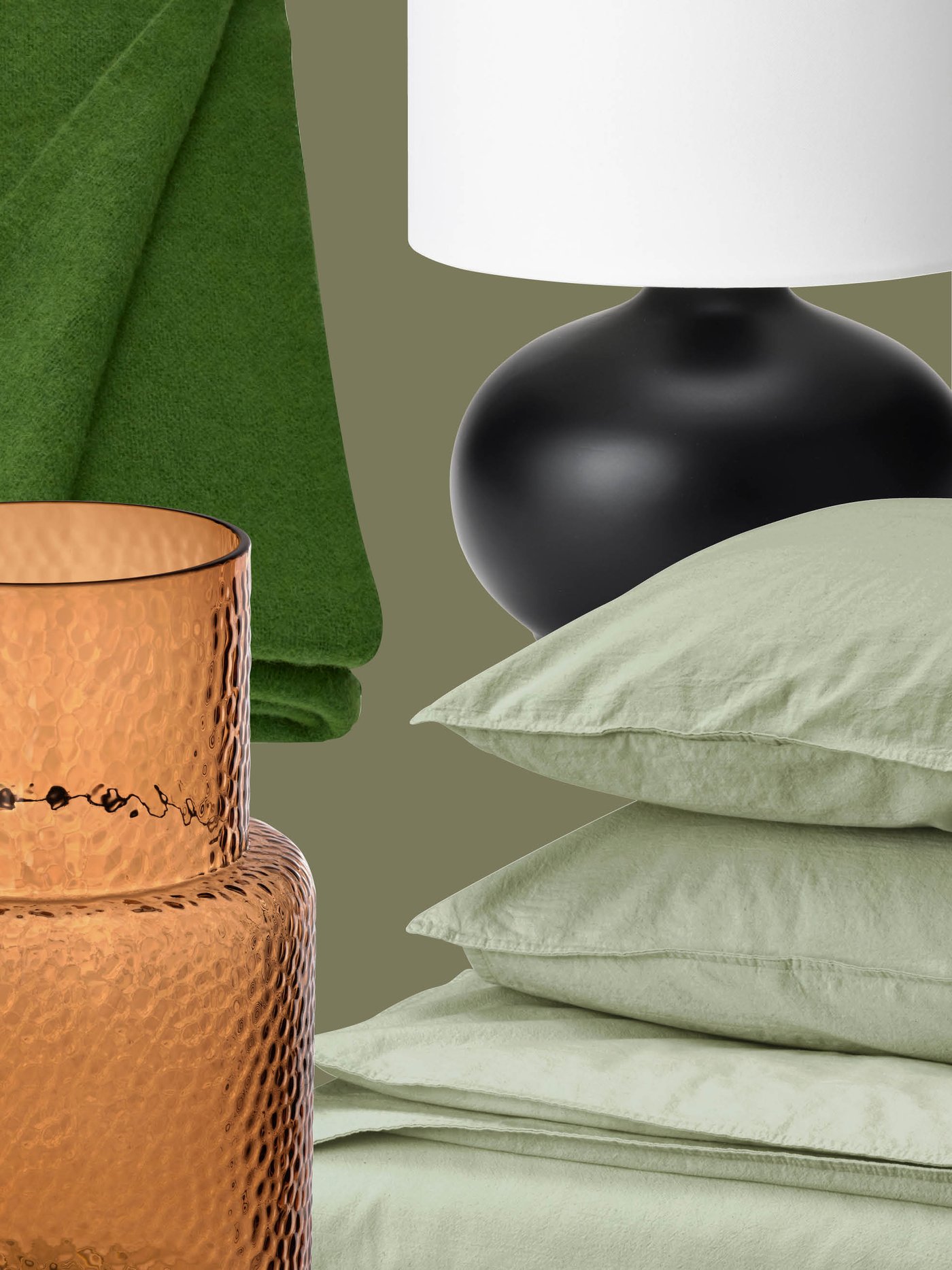 Een groene sprei, een amberkleurige vaas van gestructureerd glas, een zwarte lampvoet met een witte kap en lichtgroen IKEA-beddengoed zorgen voor een warme en harmonieuze sfeer in het interieur.