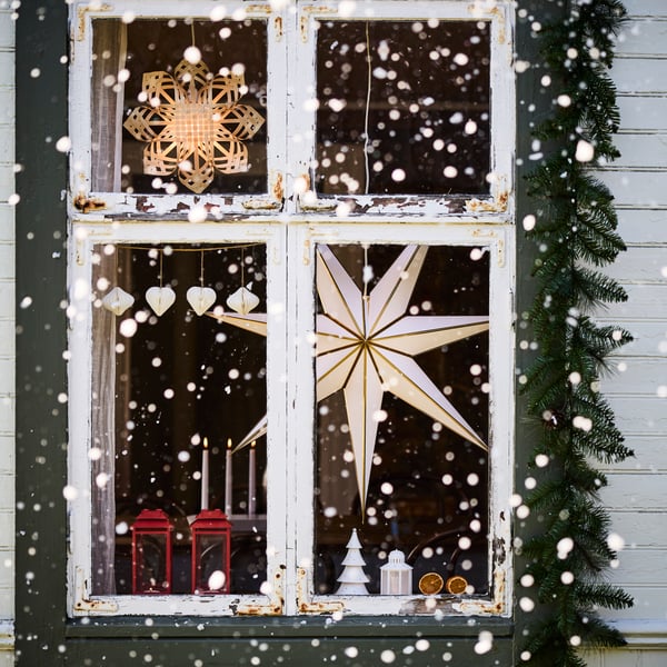 En adventsstjerne lyser inne i et juledekket hus.