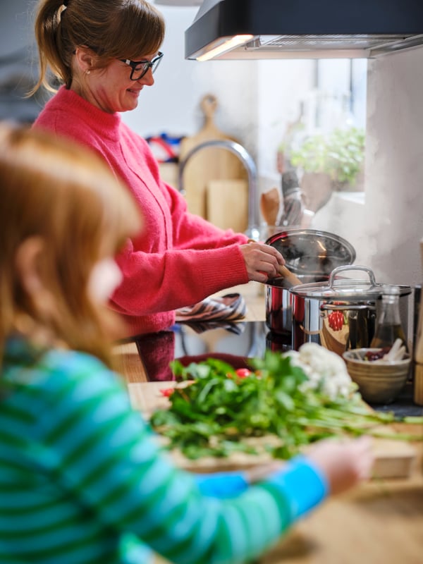 A mother and child cook using IKEA 365+ cookware in the kitchen.