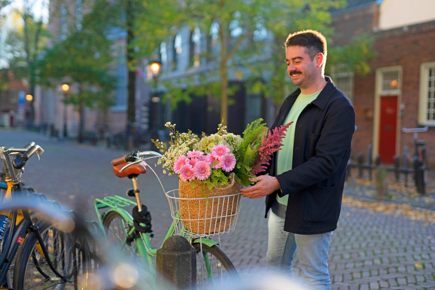 Un uomo sistema dei fiori freschi nel cestino della bici.