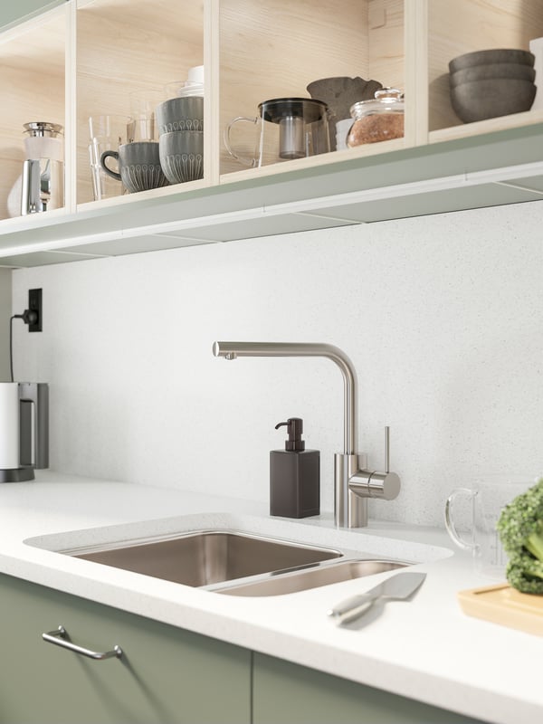 A white worktop with mineral/glitter effect, a stainless steel sink with a stainless steel-coloured kitchen faucet.