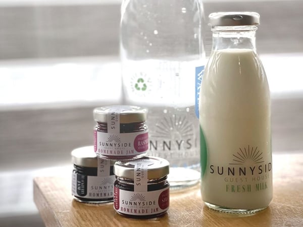 A glass bottle of fresh milk and an assortment of jams produced by Sunnyside.