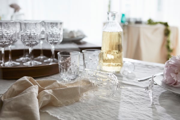 Vacker bröllopsdukning med romantiska glas och en SÄLLSKAPLIG karaff fylld med dryck.