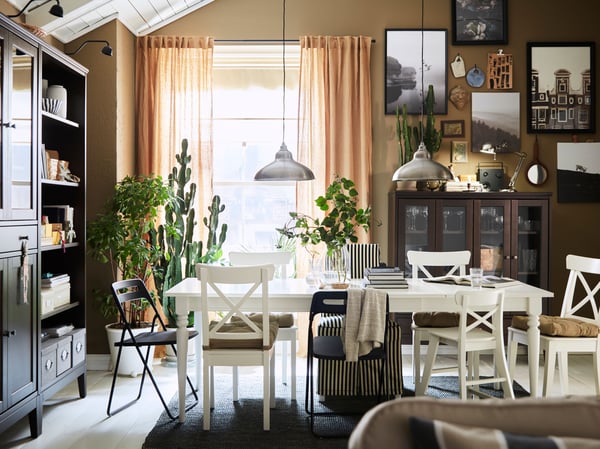 An extended INGATORP extendable table and chairs including four white INGOLF chairs stand in a traditional-style dining area.