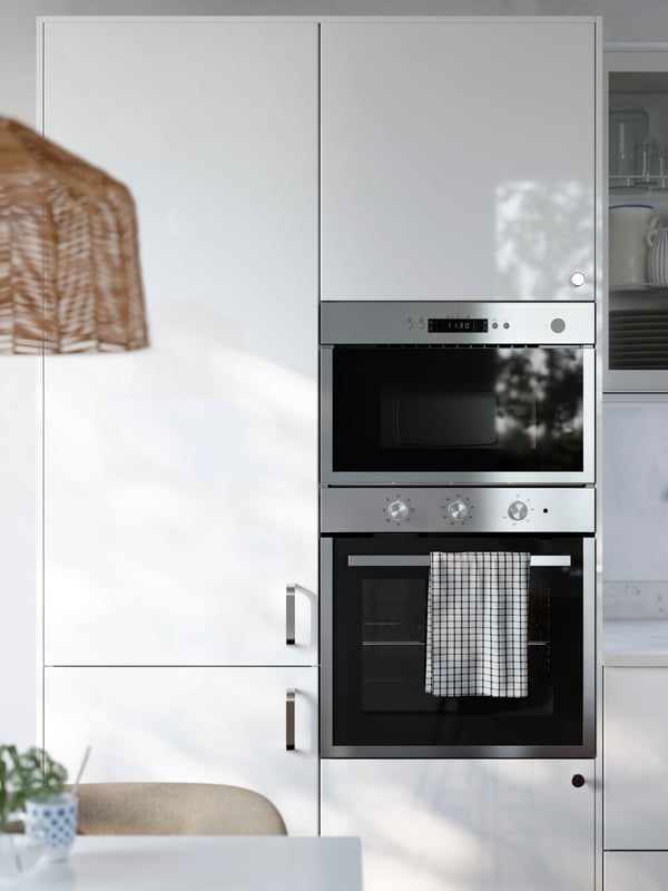 A kitchen has cabinets with glossy RINGHYLT fronts with an integrated fridge/freezer, a built-in oven and microwave oven.