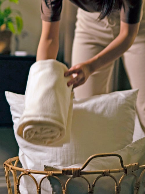 Woman taking a THORGUN throw out from a wicker basket.