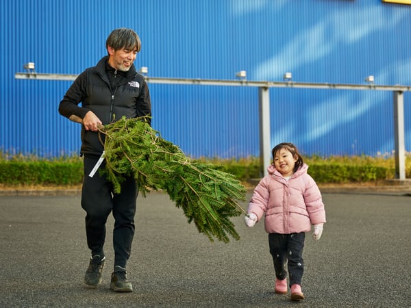 親子がもみの木を抱えて、イケア店舗の前を歩いている