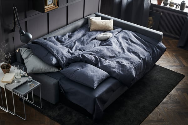 FRIHETEN corner sofa bed with storage in dark grey, in a dark grey living room