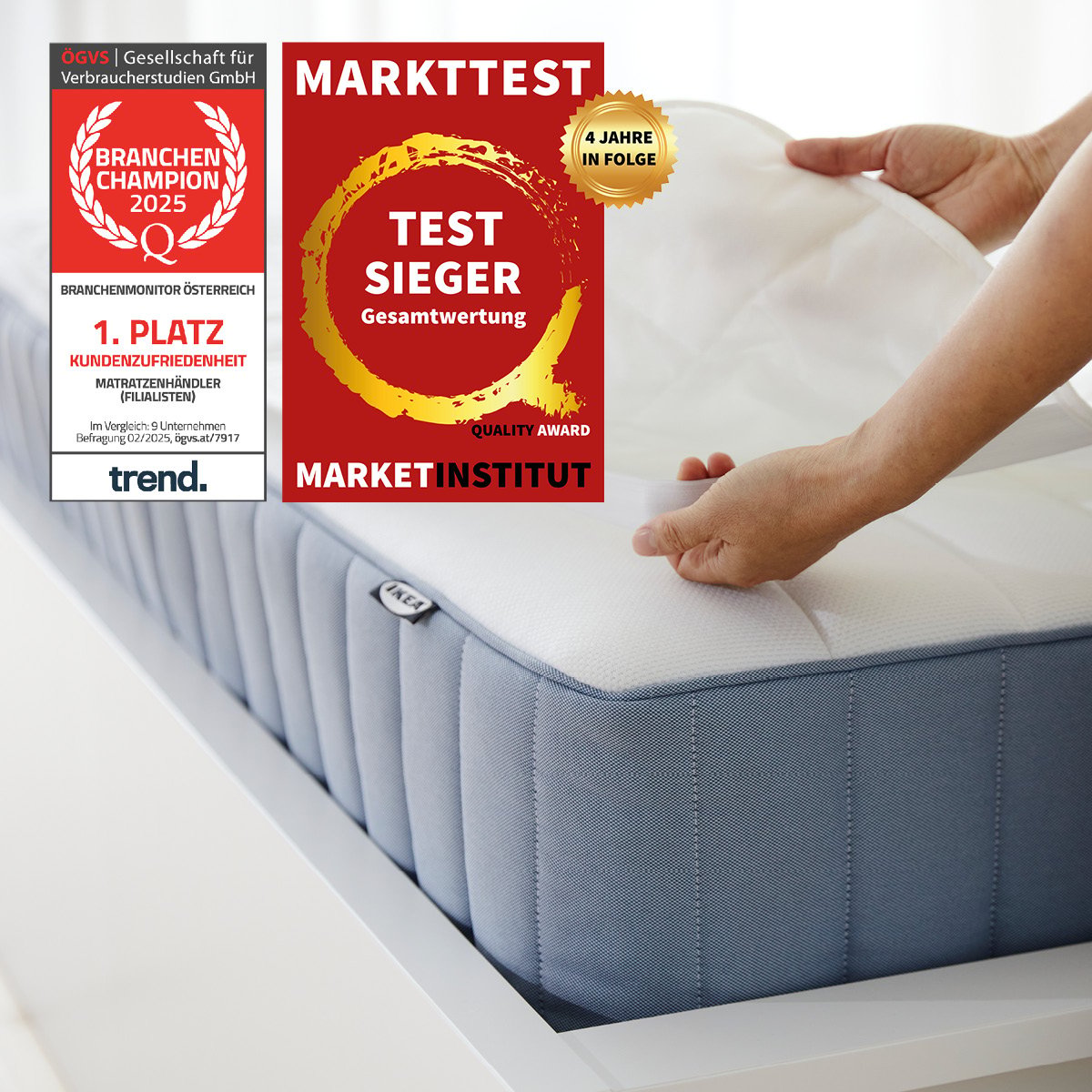 Zwei Hände legen ein weißes Kissen auf eine moderne Matratze, während daneben Qualitätsauszeichnungen eingeblendet sind. Links und rechts sind rote und goldene Siegel mit Texten wie „MARKTTEST“, „TESTSIEGER“ und „1. Platz Kundenzufriedenheit“ zu sehen.