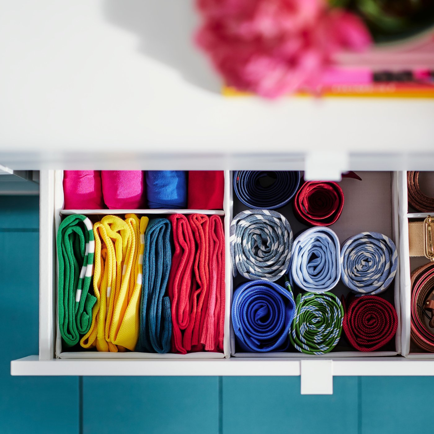 Bild tagen uppifrån på en utdragen byrålåda med SKUBB förvaring som innehåller färgglada kläder.