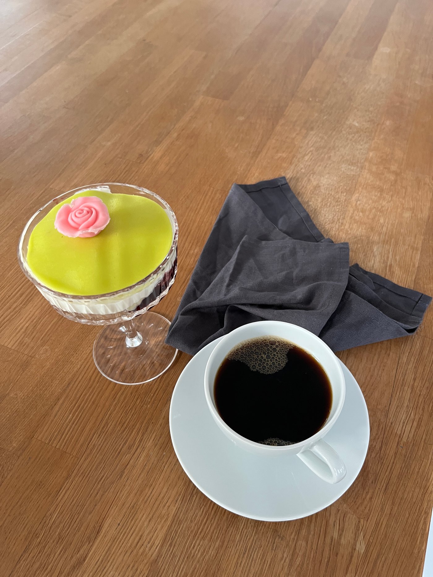 En färdig prinsesstårta i glas serverad i ett SÄLLSKAPLIG glas och bredvid står en kopp med kaffe.