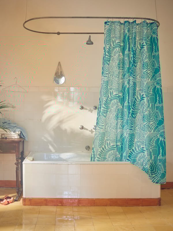Una tenda doccia GATKAMOMILL con motivo a foglia turchese e bianco appesa sopra una vasca da bagno.