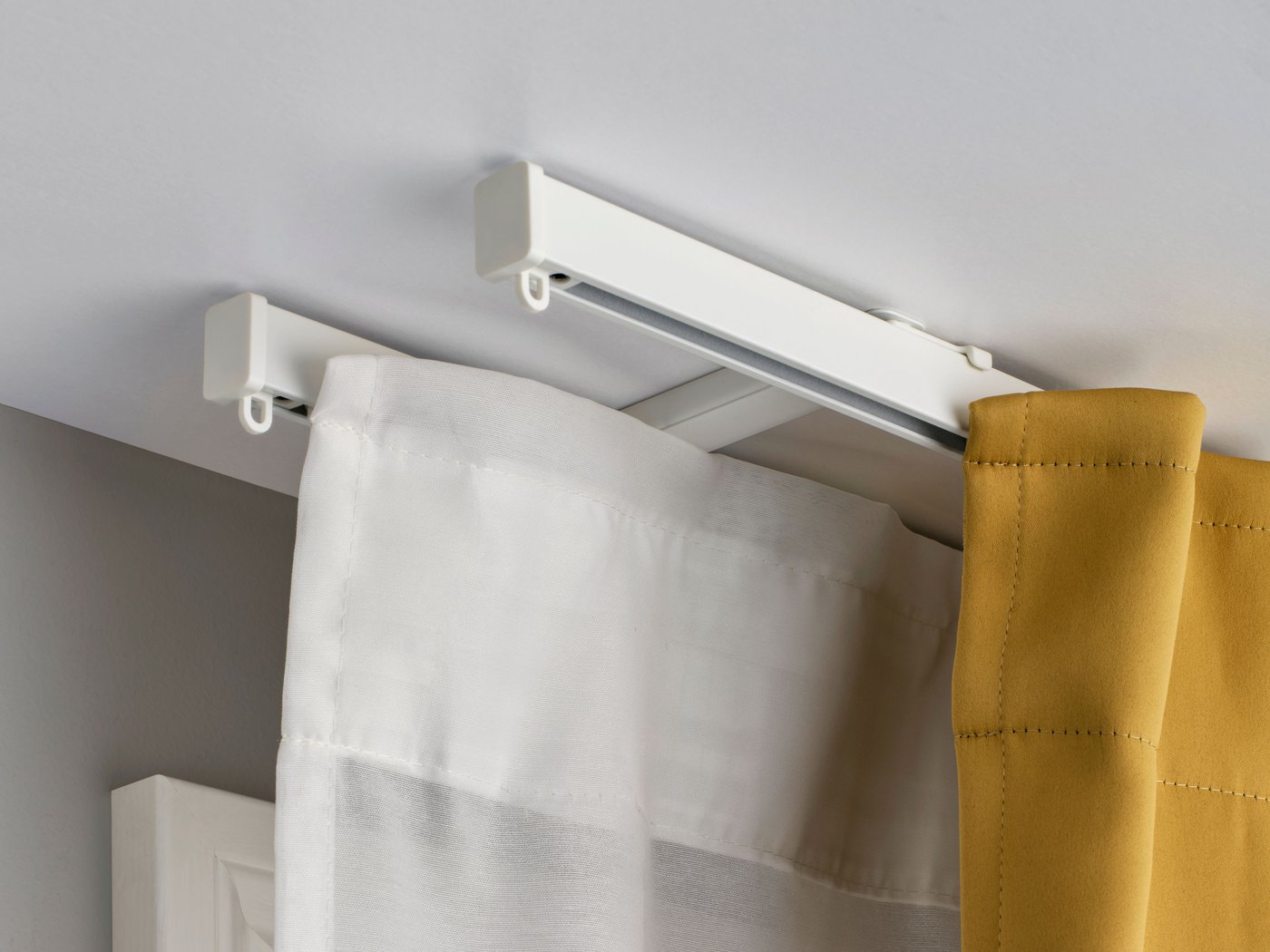 A white VIDGA ceiling bracket for 2 curtain rails