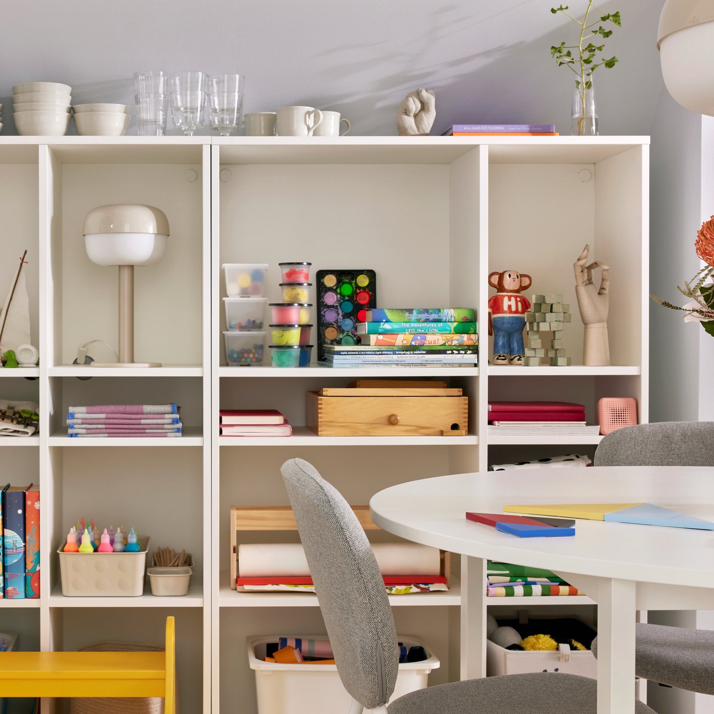 In einem Familienesszimmer steht ein VIHALS Stuhl an einem runden VIHALS Tisch vor zwei VIHALS Regalen in Weiß.