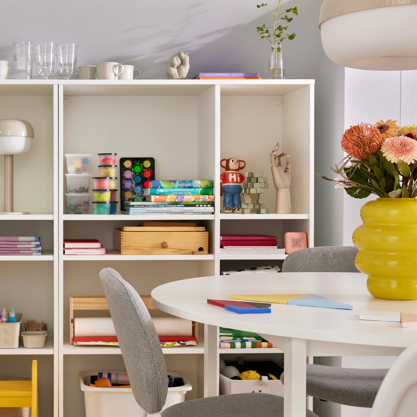 A VIHALS chair stands at a round VIHALS table in front of two white VIHALS shelving units in a small family dining room.