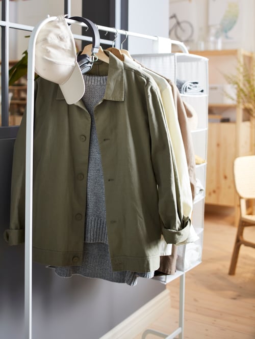 Hallway area featuring a white clothes with a cap, headphones, clothes, and a storage with compartments, and a cabinet.