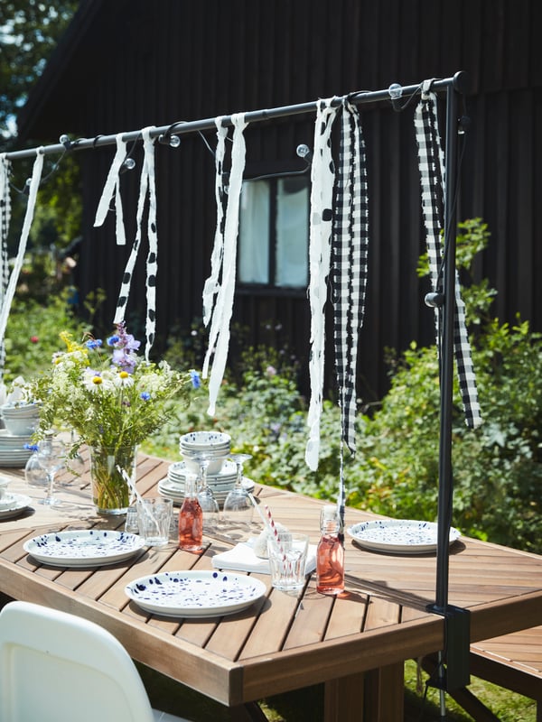 NORRMANSÖ wood table in the garden is set and decorated for a Midsummer celebration.