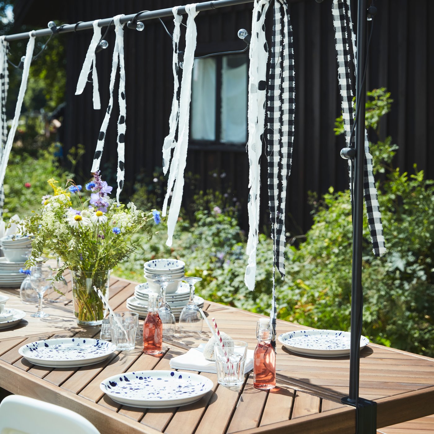 NORRMANSÖ wood table in the garden is set and decorated for a Midsummer celebration.