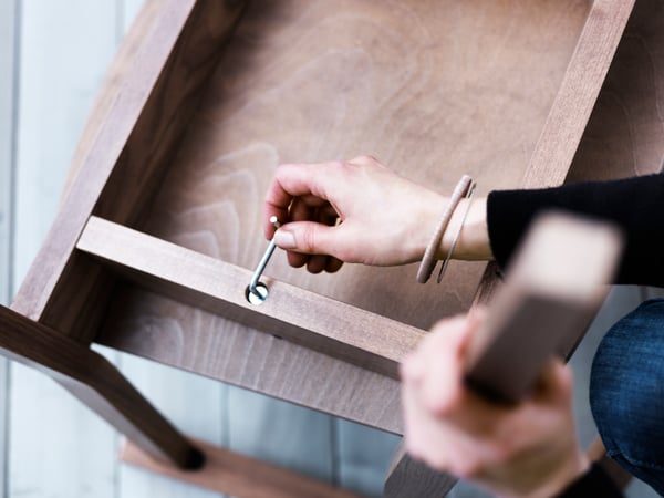 Una persona sta montando un mobile IKEA in legno scuro