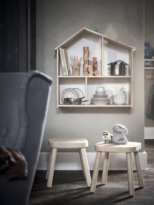 Children’s room with doll’s house, wall shelf, children’s stool and armchair, soft toys, books, crayons, pots, pans, plates.