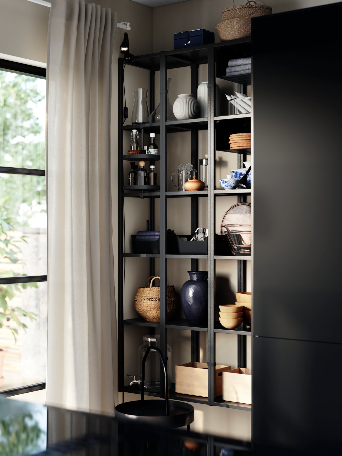 ENHET väggmonterade hyllor med hög ram som håller vaser och köksredskap, bredvid ett fönster med gardiner och en svart bänkskiva.