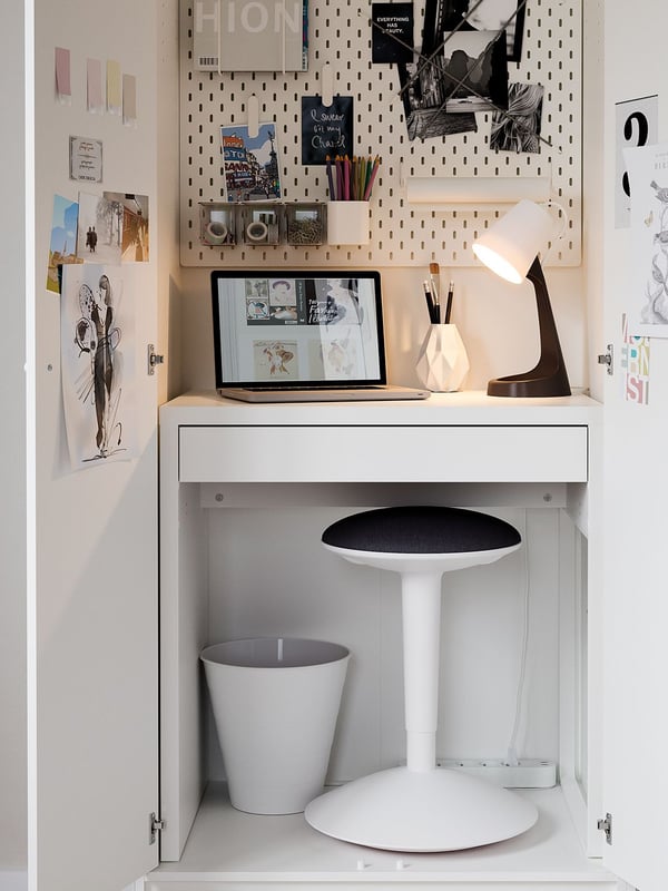 A workspace built into a cupboard with a MICKE desk and a NILSERIK work stool, FNISS waste bin, and a SKÅDIS pegboard.