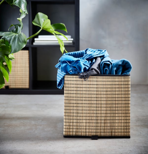 Brown GNABBAS basket sitting on floor. Blue fabric in box.