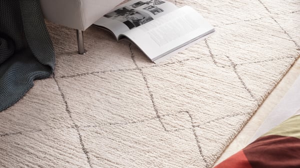 Beige TVERSTED-matto makuuhuoneen lattialla.