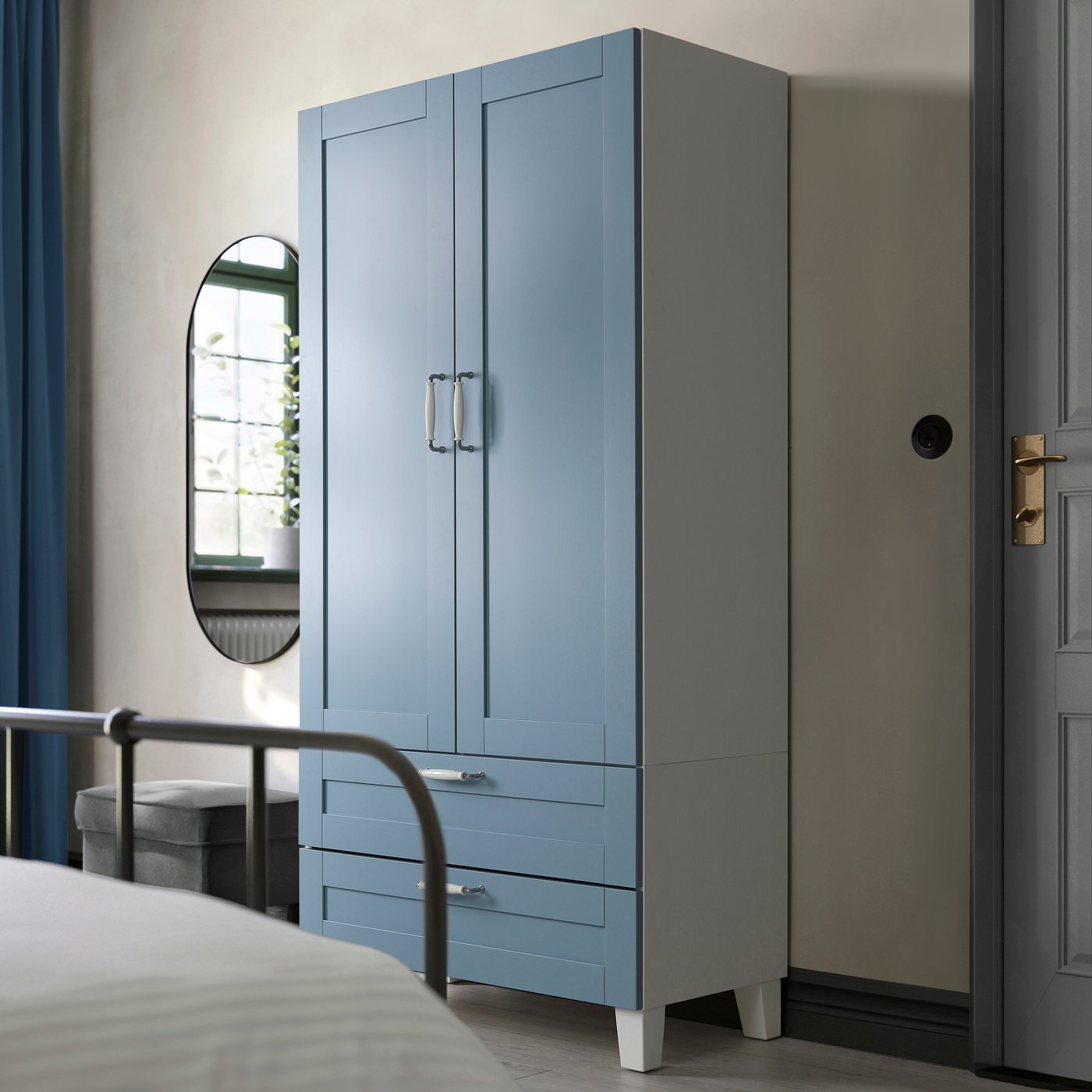 Un armadio PLATSA bianco/blu Sannidal con 2 ante e 2 cassetti con accanto uno specchio appeso alla parete.