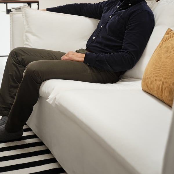 En man sitter i en vit BACKSÄLEN 3-sits soffa. 
