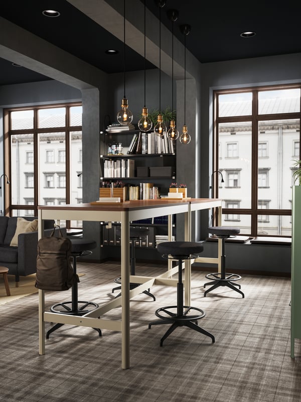 Two IDÅSEN tables are placed together close to a large window creating a standing meeting zone.