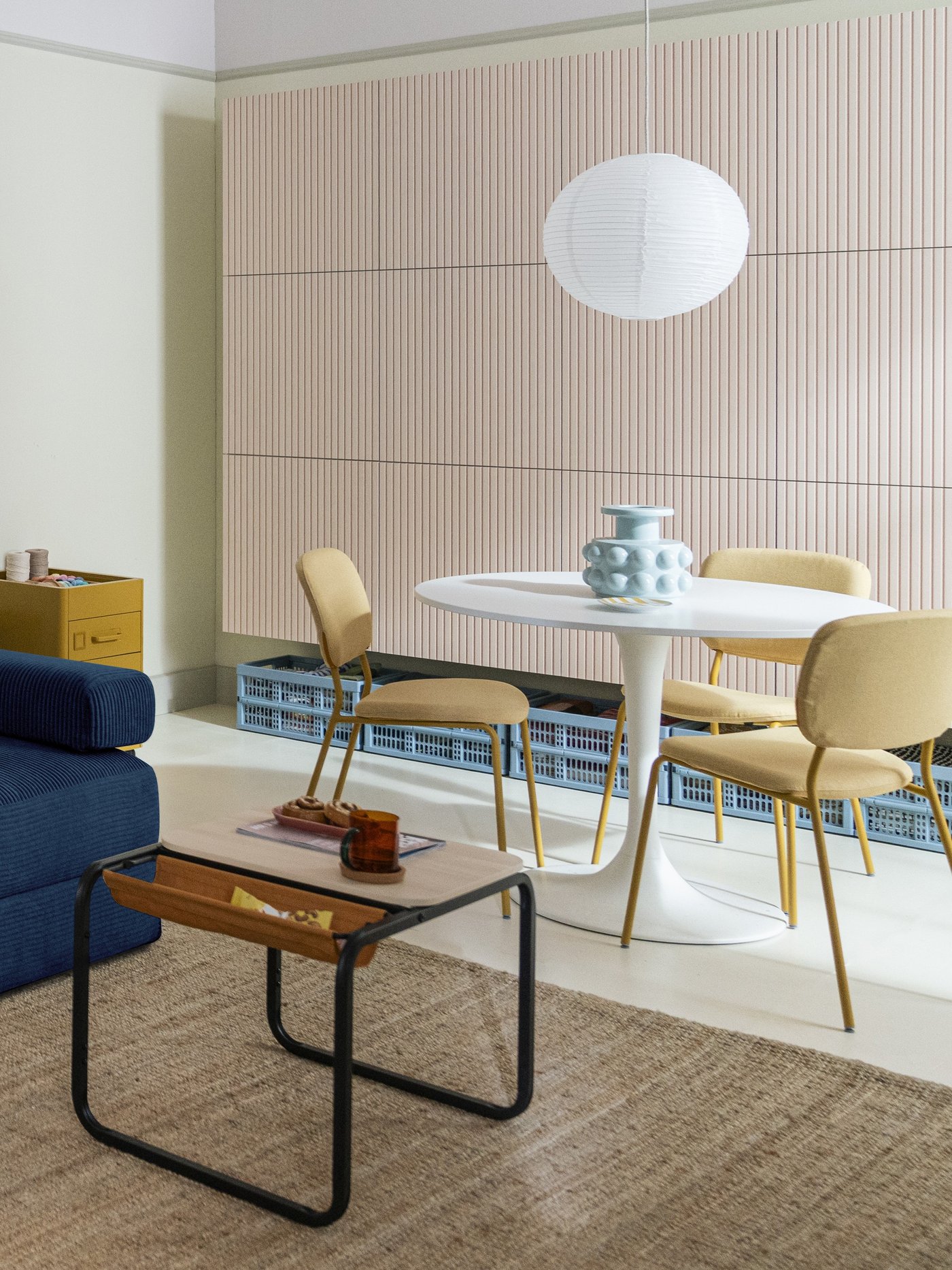 Sedia VIHALS gialla accostata a un tavolo rotondo bianco nella zona pranzo di un soggiorno luminoso.