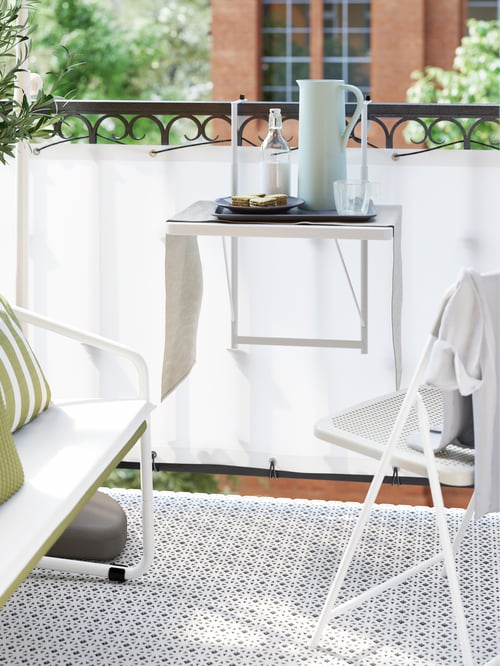Outdoor area featuring a balcony table with a vacuum flask surrounded by an outdoor two-seat sofa and a beige chair.