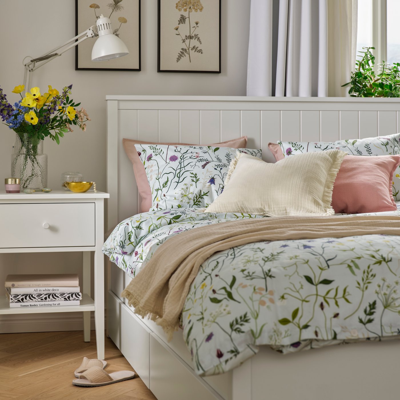 Una camera accogliente con comodino e struttura. La biancheria da letto MATTOXBÄR è sul letto con cuscini e un plaid.