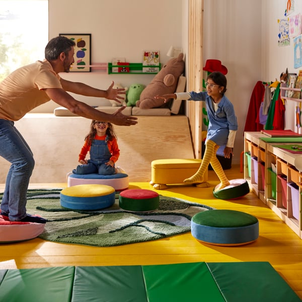 In a parent and two children play a game of Floor is Lava while using GREJSIMOJS floor cushions and a GRESIMOJS rug.