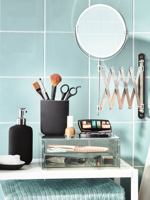 A green-tiled bathroom with a wall-fitted FRÄCK mirror above a GODMORGON mini chest filled with make-up accessories.