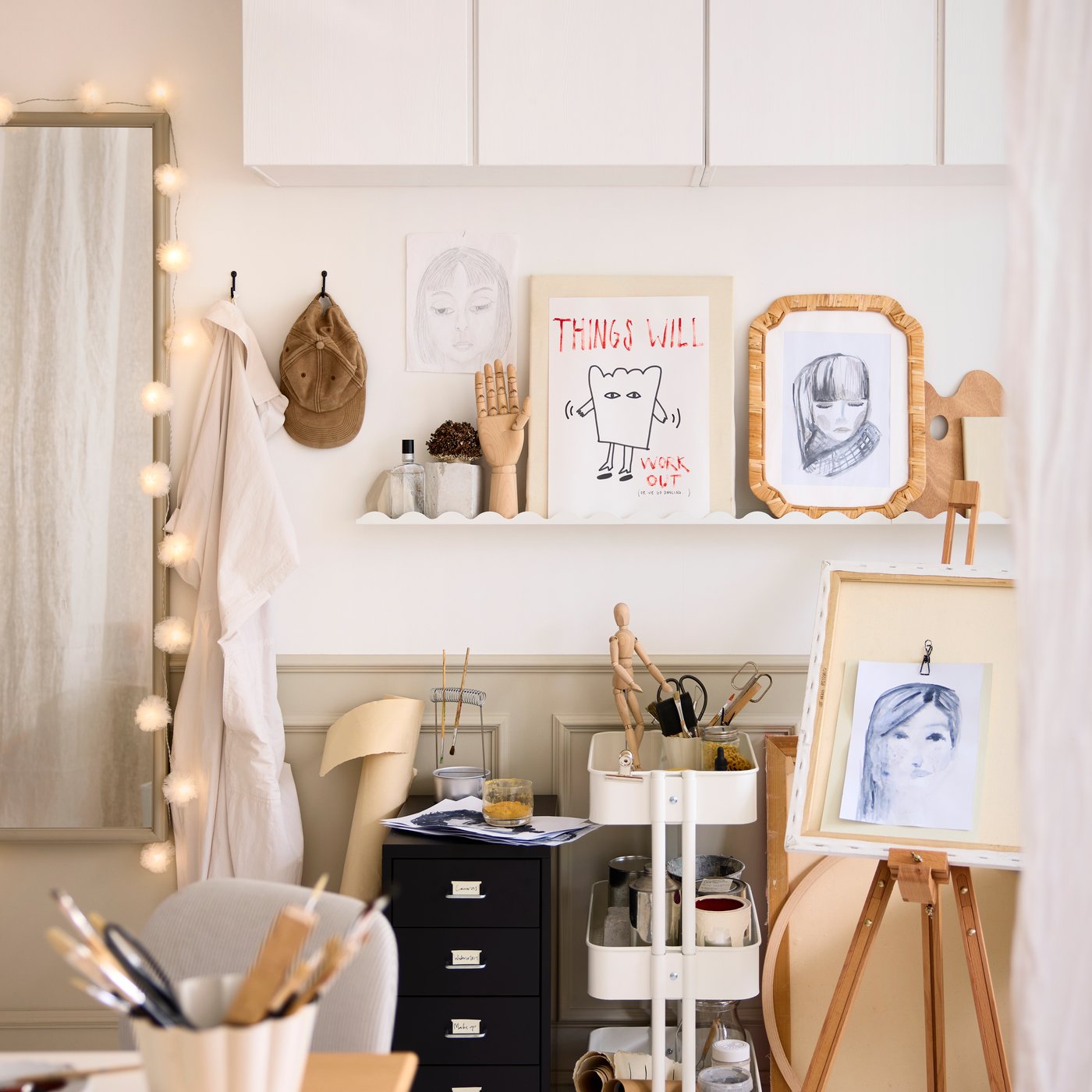 Et hobbyområde i et soveværelse med en hvid DAGGKAPRIFOL billedhylde, der udstiller kunst og dekorative genstande på væggen.