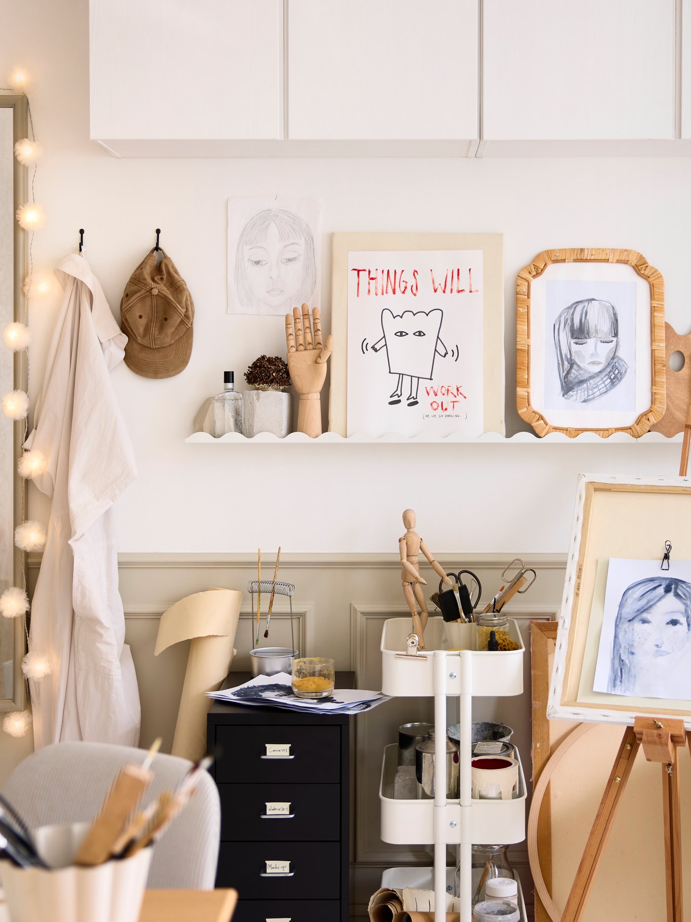 Een slaapkamer met een witte DAGGKAPRIFOL schilderijenplank waarop kunstwerken en wanddecoratie staan.