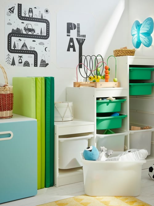 Children’s room with white storage frames, plastic storage boxes, posters, folding gym mat, toys and wall lamp.