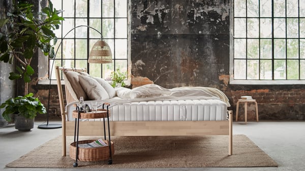 A black SKAFTET floor lamp base, arched in the bedroom