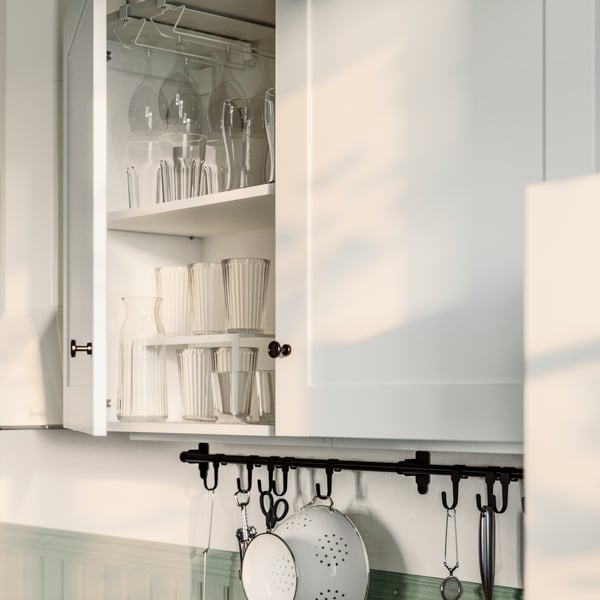 A KNOXHULT wall cabinet has one door open and a PÅLYCKE clip-on multi-purpose rack and a VARIERA insert shelf divider inside.