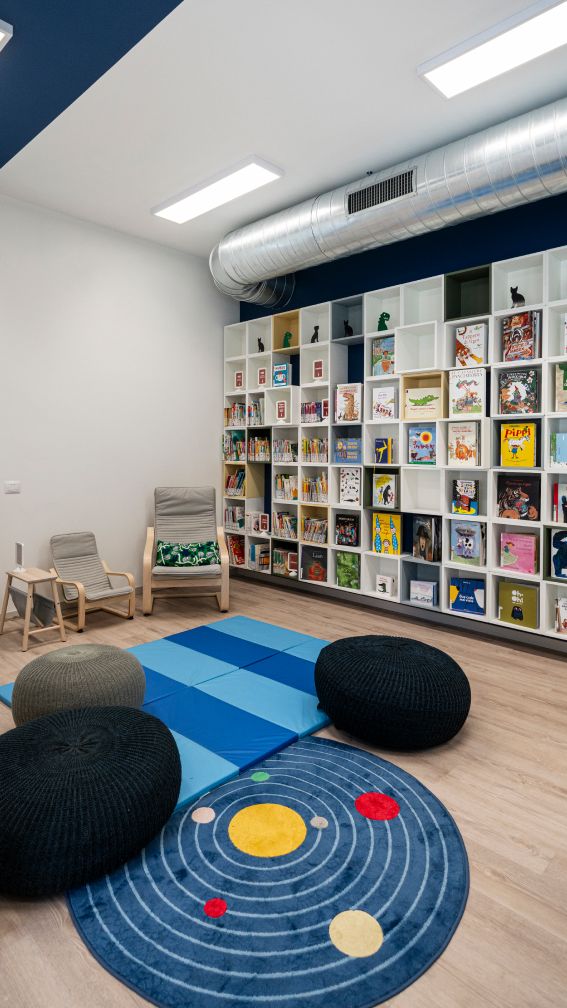 Tappeti disposti davanti a un'enorme libreria con libri per bambini.