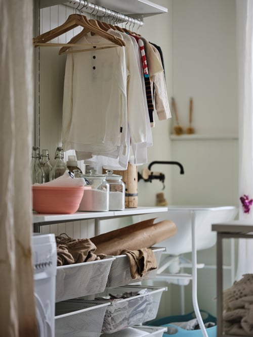 A modern laundry room that features a wardrobe combination, a pair of white curtains, several hangers, and a jar with a lid. 